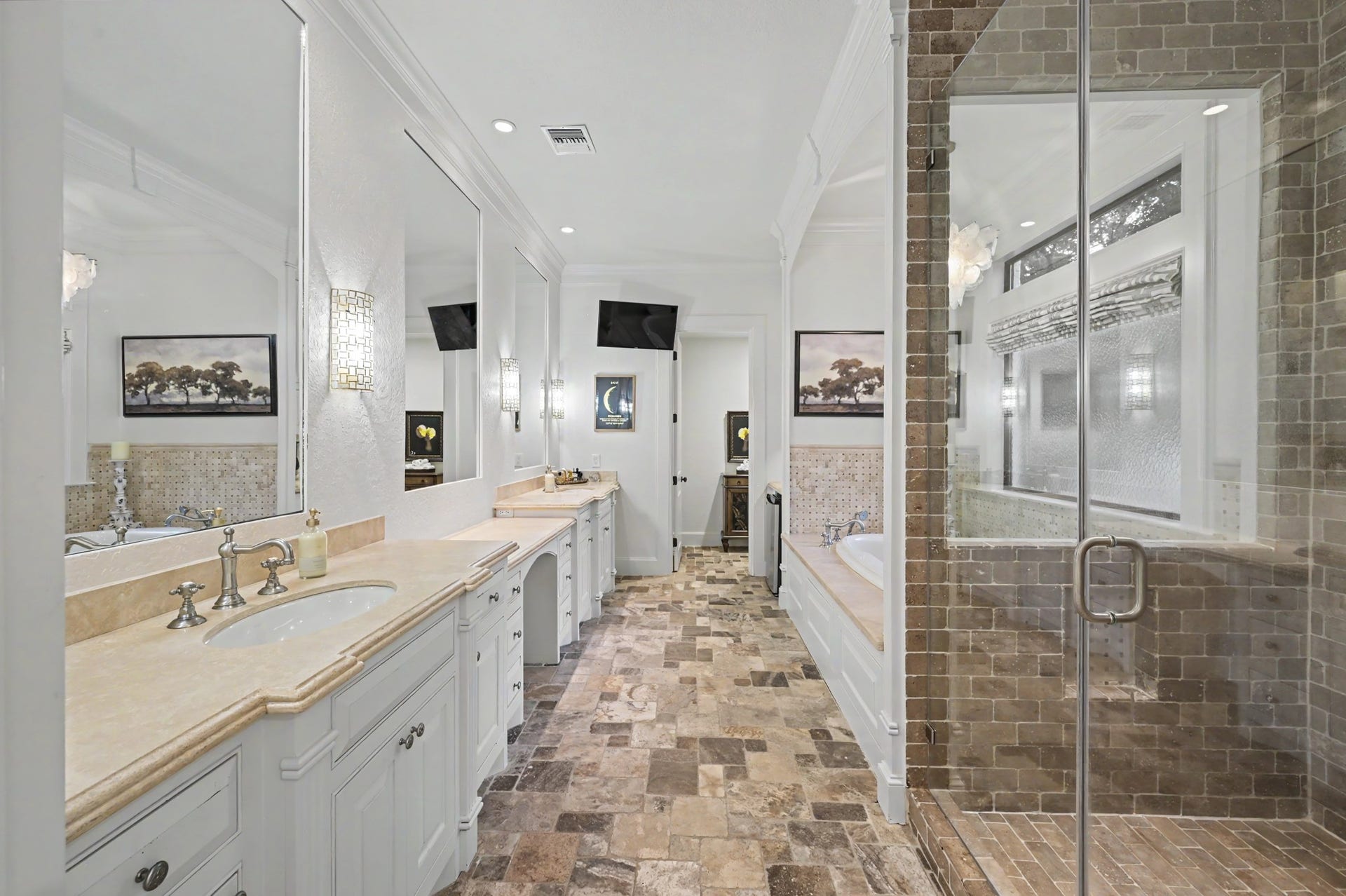 Spacious primary bath featuring dual vanities, a large walk-in shower, soaking tub, and elegant natural stone finishes throughout.