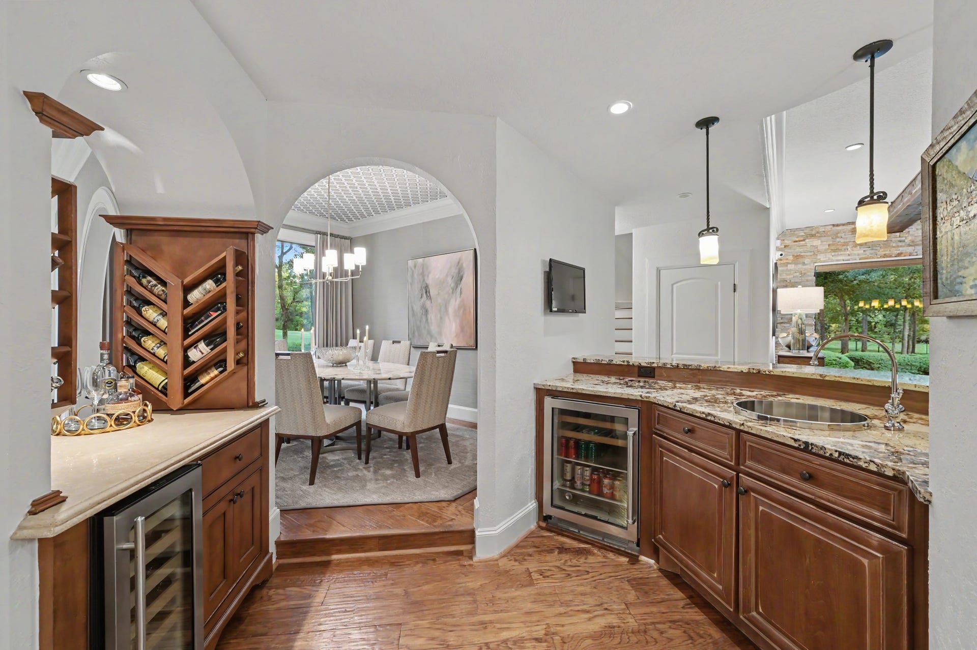 Custom wet bar featuring rich wood cabinetry, granite countertops, dual beverage coolers, and built-in wine storage, conveniently positioned between the formal dining and living areas.