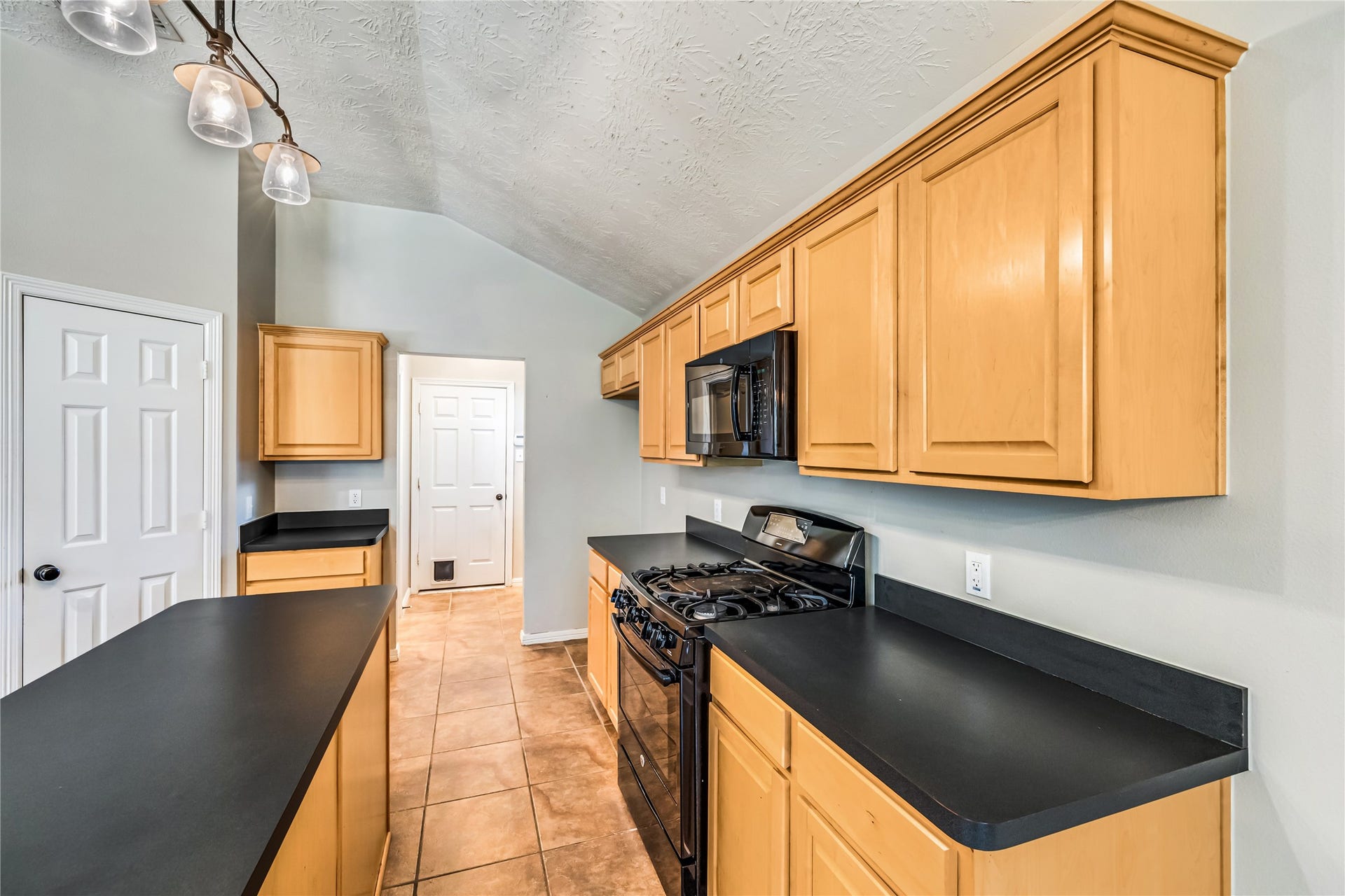 914 Mesquite Drive, Magnolia, TX 77354 Kitchen has an island, pantry, gas range, microwave and lots of cabinet space and garage, laundry and desk access