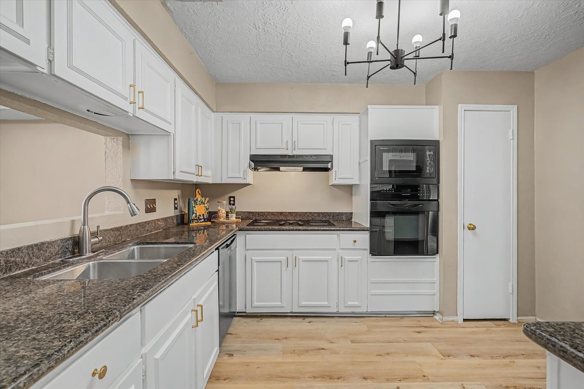 794 Thicket Lane, Houston, TX 77079 Kitchen featuring white cabinetry, granite countertops, double-basin sink, built-in appliances, and wood-look flooring.
