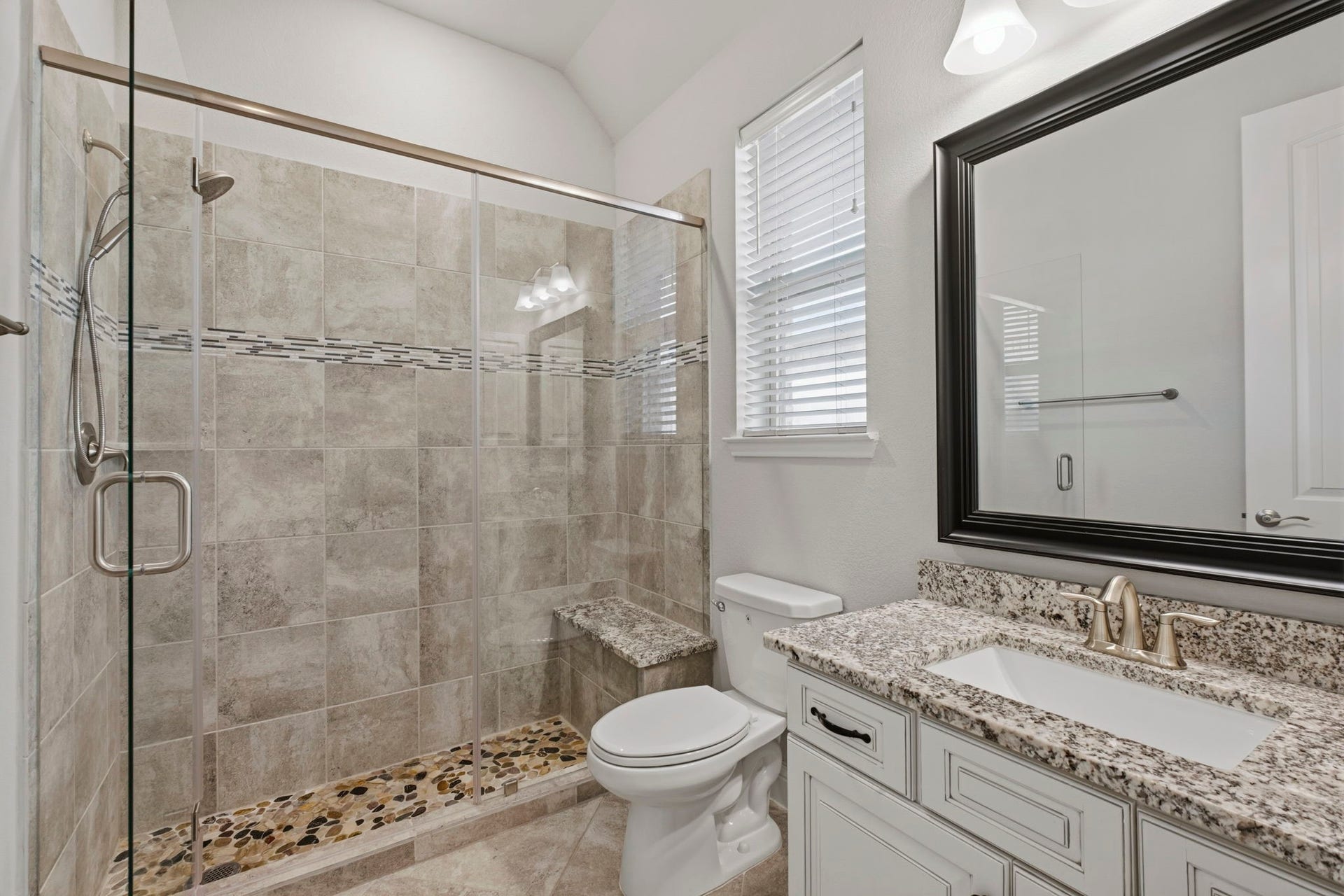 19314 Trotting Green Trail, Tomball, TX 77377 The secondary bedroom's ensuite bathroom with mudset shower complete with shower chair and cobblestone floor. All upgrades