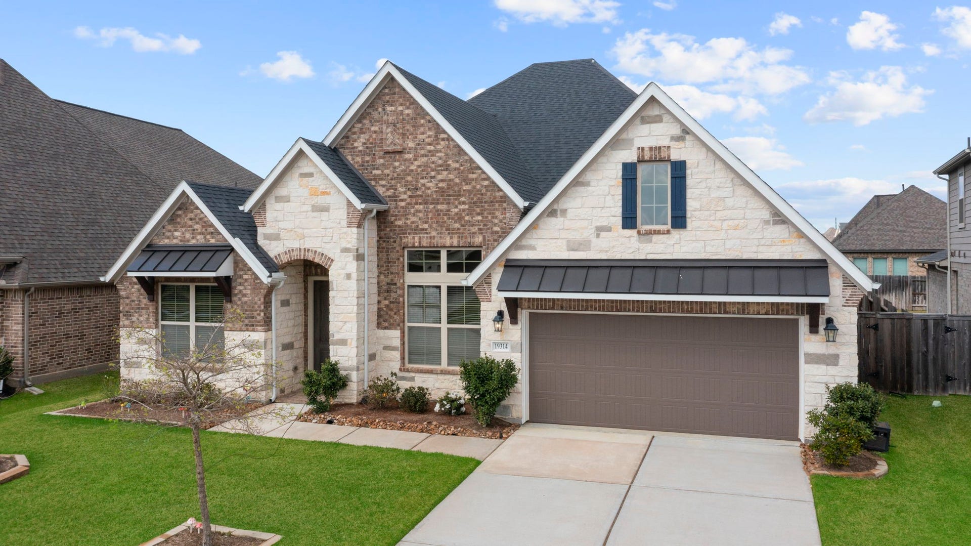 19314 Trotting Green Trail, Tomball, TX 77377 This charming home features a combination of brick and stone exterior, a gabled roof, and a two-car garage.