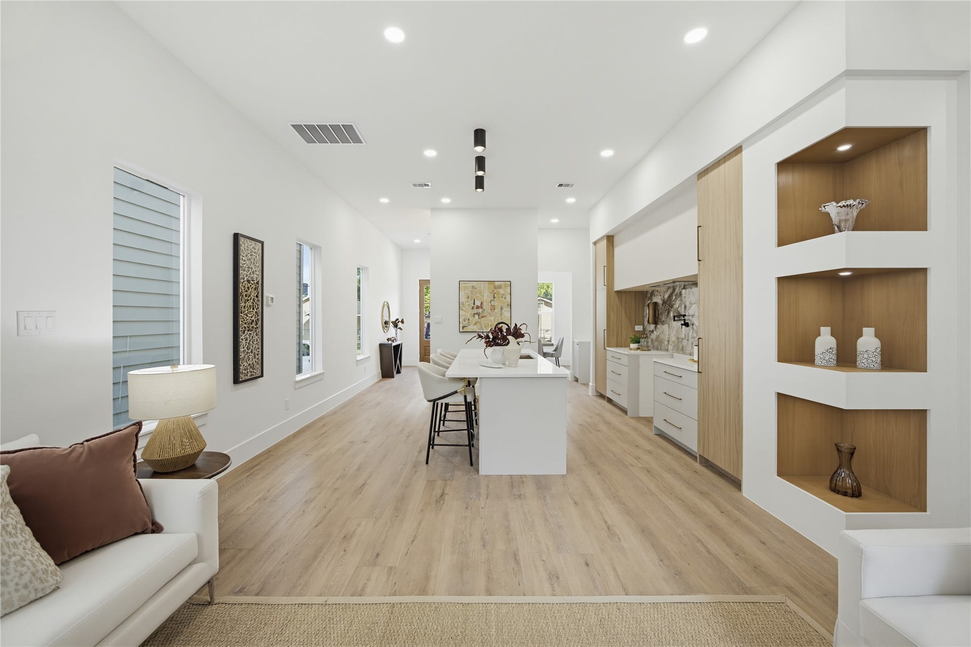1004 E 35th Street, Houston, TX 77022 Sleek and modern open-concept living space with elegant wood flooring, built-in shelving, and a stylish kitchen featuring a central island and contemporary cabinetry.