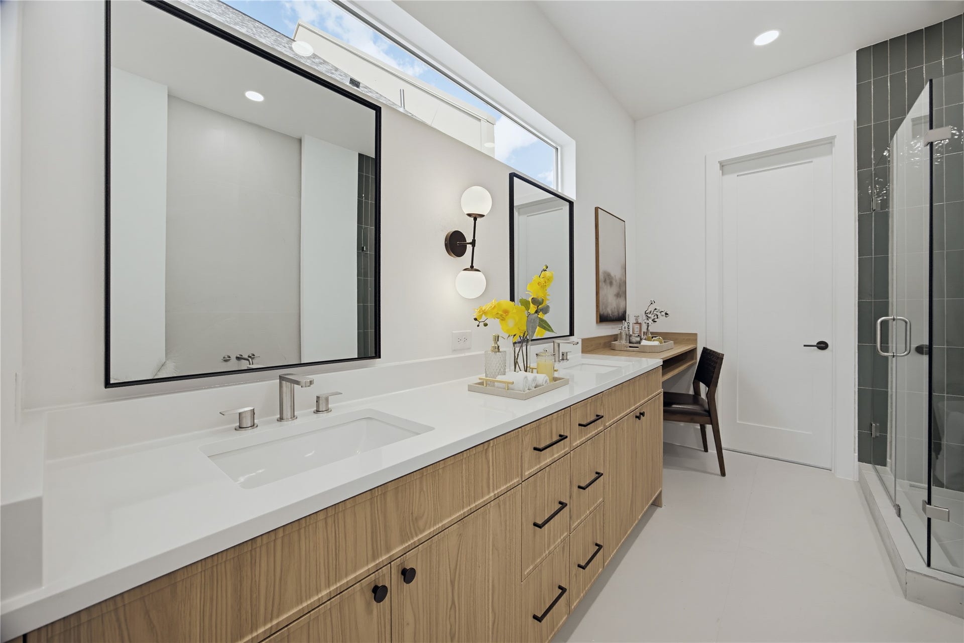 1004 E 35th Street, Houston, TX 77022 Elegant bathroom featuring a double vanity with sleek fixtures, ample storage, and a stylish glass-enclosed shower, complemented by modern lighting and a convenient makeup station.