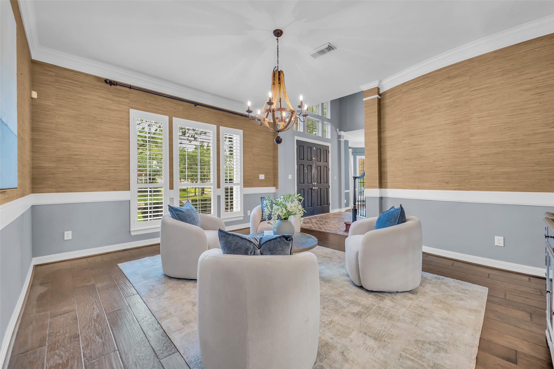 8703 Stones Throw Lane, Missouri City, TX 77459 A formal living room just off of the foyer features engineered wood flooring, custom chandelier, windows with plantation shutters, double crown molding and elegant grass cloth wallpaper.