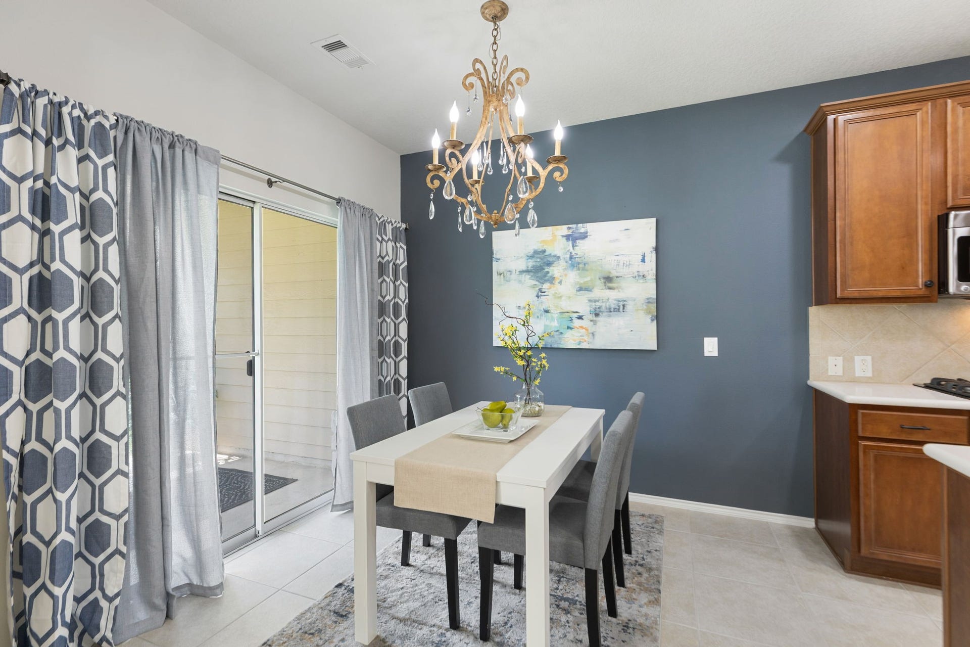 13600 Breton Ridge Street, #11A, Houston, TX 77070 The dining area is a gorgeous focal point with a modern vibe chandelier and a stylish blue accent wall, featuring a sliding glass door that opens to your covered patio.