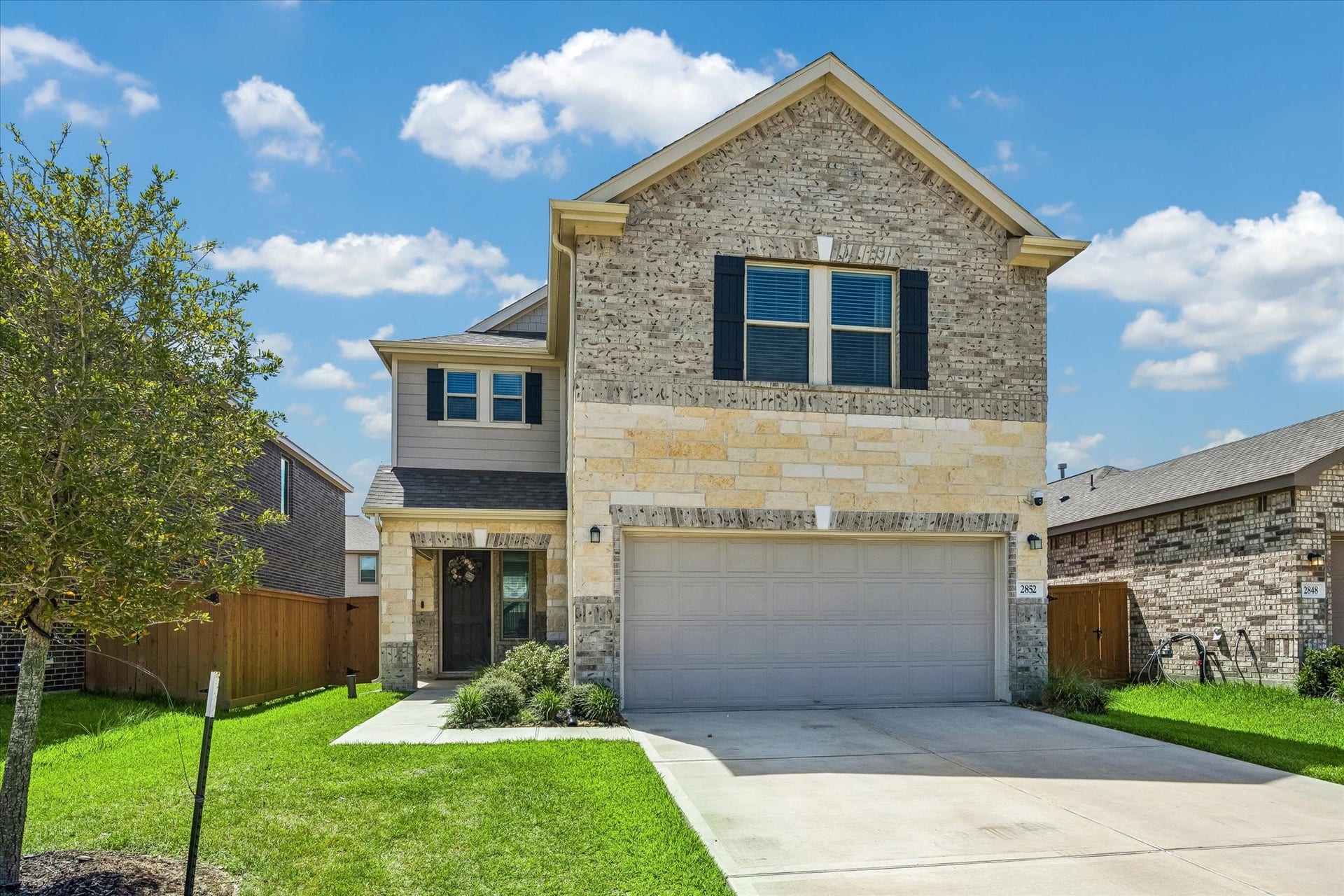 2852 Grand Anse Drive, Katy, TX 77493 Two-story home featuring a beautiful brick and stone exterior, two-car garage, and well-maintained front lawn.