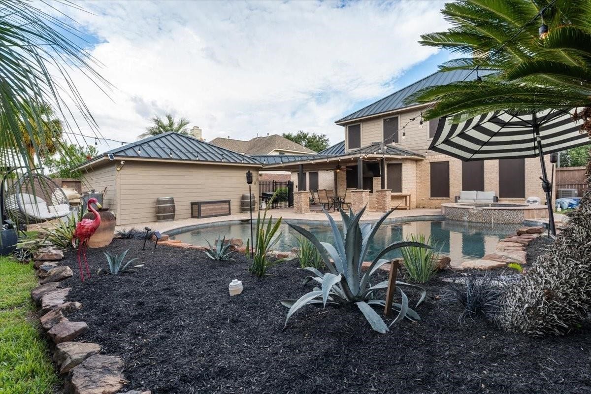 2437 La Rochelle Court, Seabrook, TX 77586 Beautifully landscaped pool area with stone edging, palm trees, and space for outdoor relaxation.