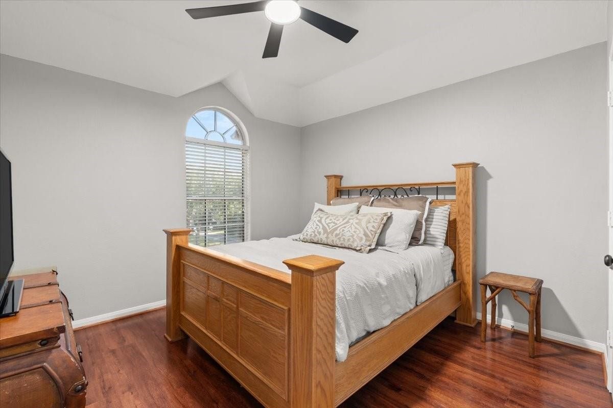 2437 La Rochelle Court, Seabrook, TX 77586 Secondary bedroom features an arched window, vaulted ceiling, and warm wood flooring.
