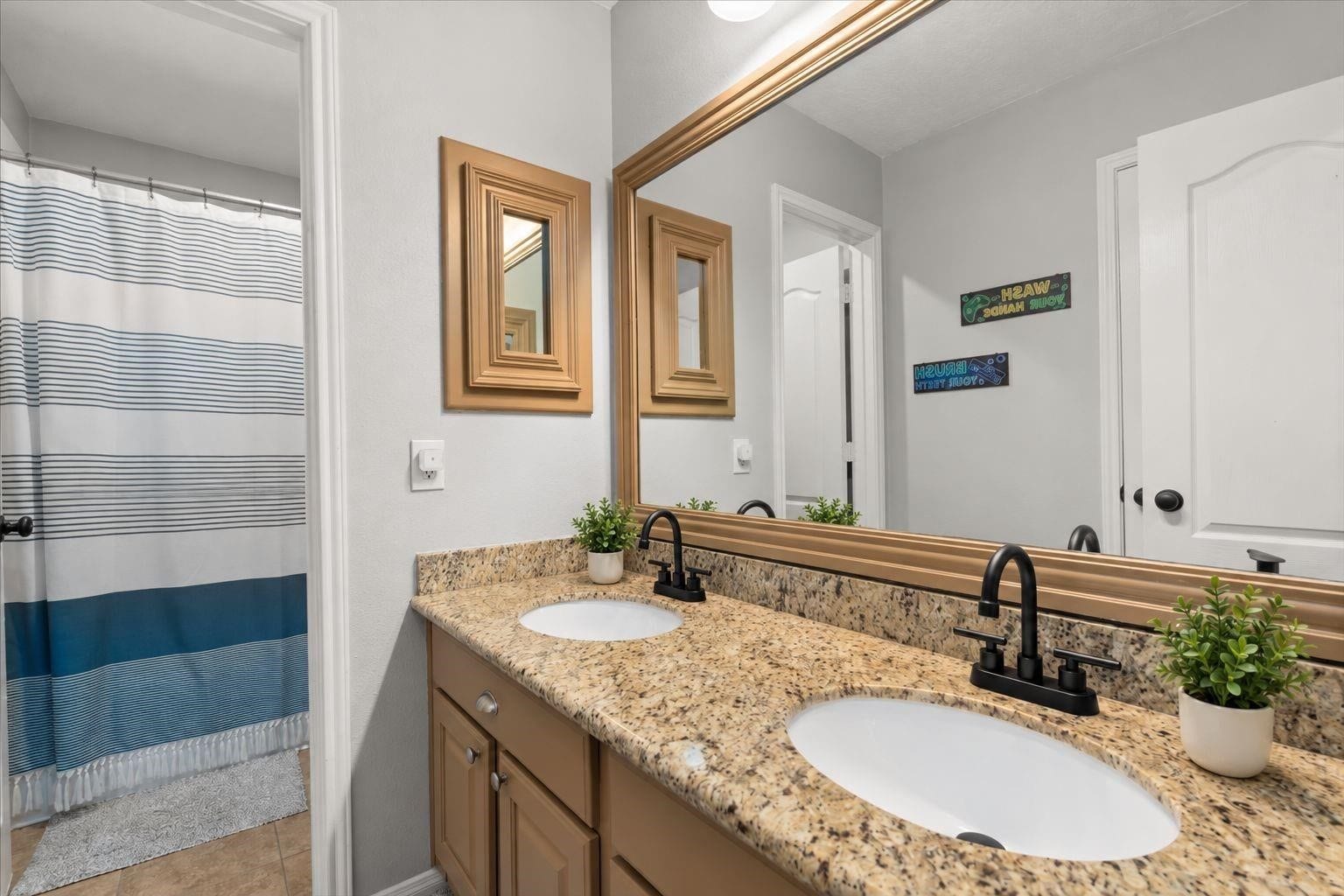 2437 La Rochelle Court, Seabrook, TX 77586 Secondary bathroom has a double-sink granite vanity and adjacent tub and shower area.