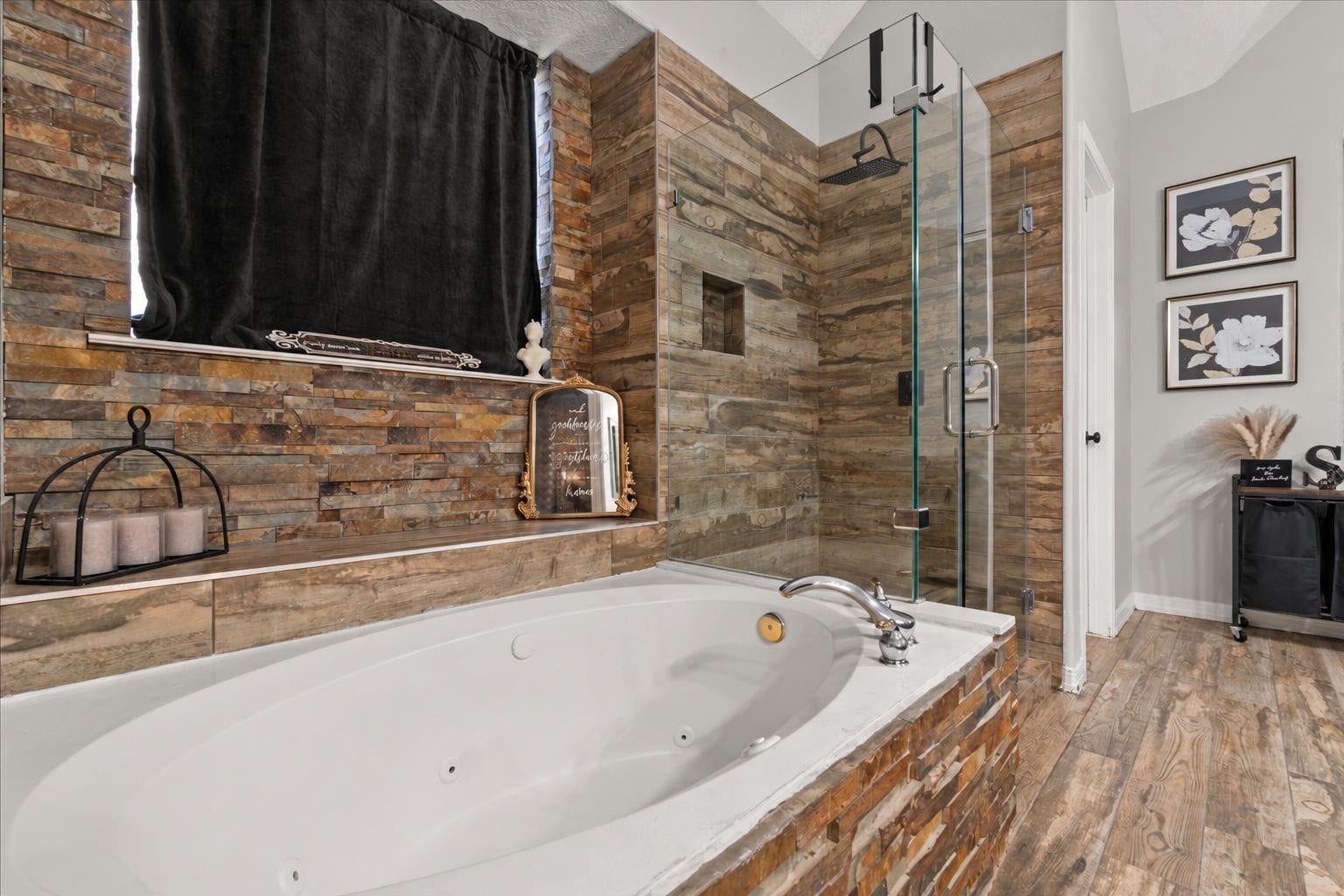 2437 La Rochelle Court, Seabrook, TX 77586 A soaking tub sits beside a glass-enclosed shower with coordinating stone and wood-look finishes.