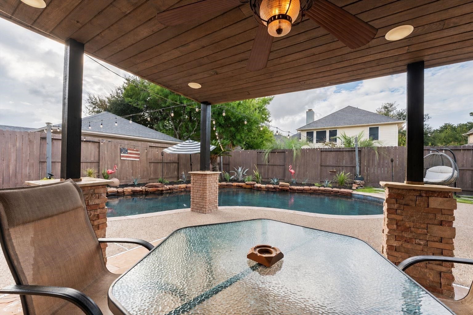 2437 La Rochelle Court, Seabrook, TX 77586 Enjoy views of the pool from the covered patio with its wood-paneled ceiling and ceiling fan.