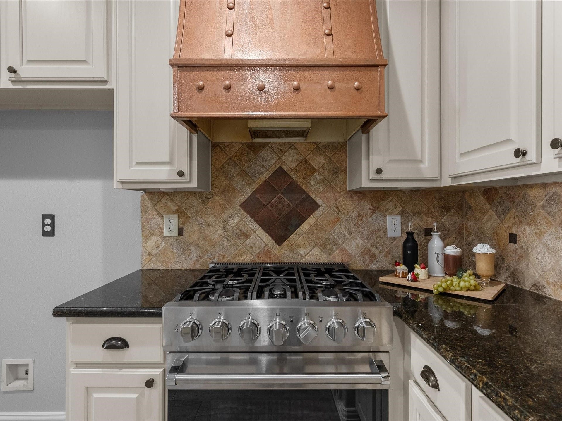 2437 La Rochelle Court, Seabrook, TX 77586 Kitchen focal point features a seven-burner Viking gas range, custom copper hood, and decorative tile backsplash.