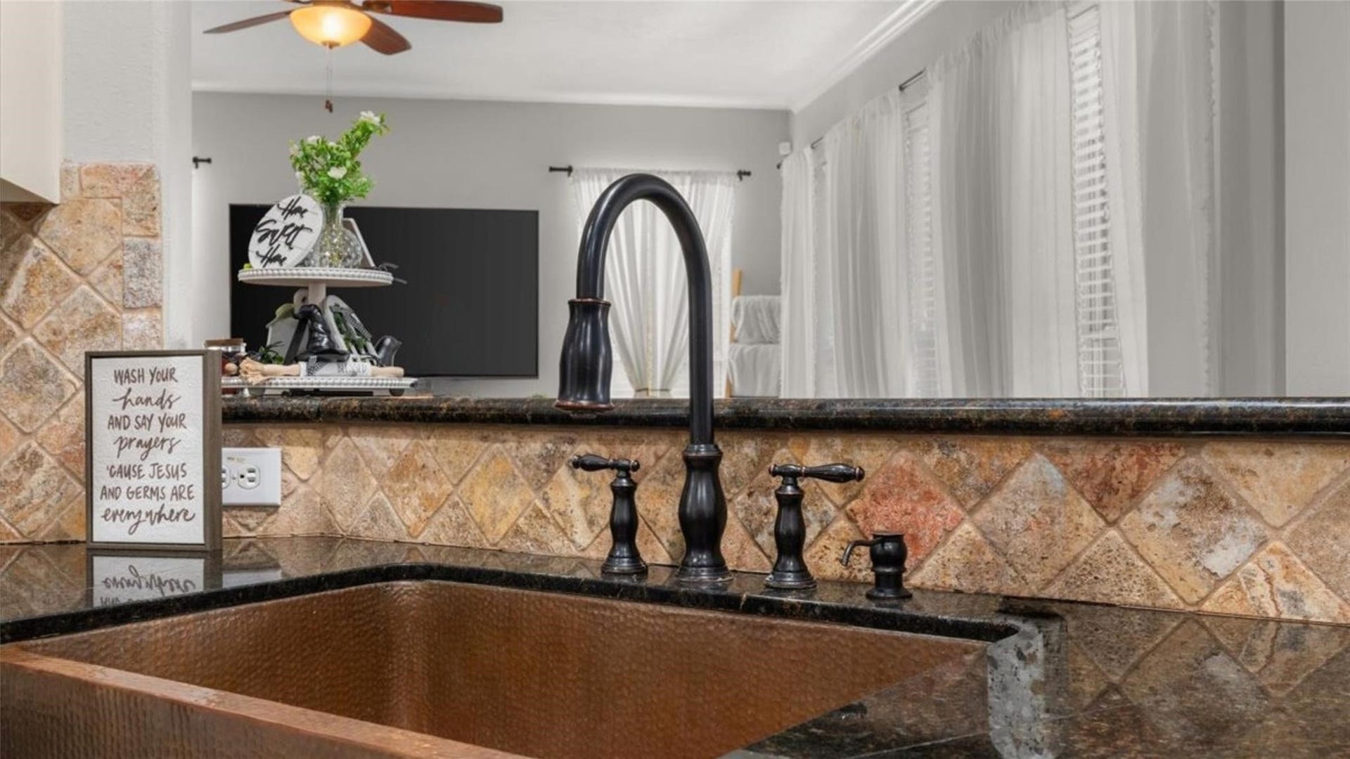 2437 La Rochelle Court, Seabrook, TX 77586 Distinctive hammered copper apron-front sink pairs with granite counters and a decorative tile backsplash.