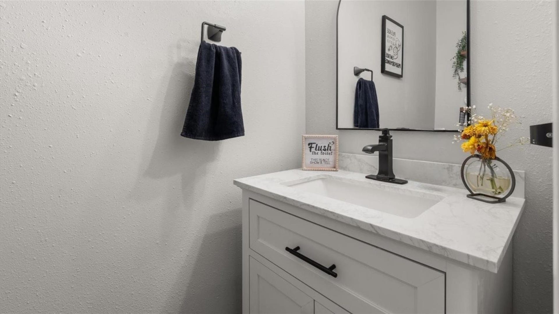 2437 La Rochelle Court, Seabrook, TX 77586 Stylish half bath features a white vanity, stone-look counter, and contrasting black fixtures.