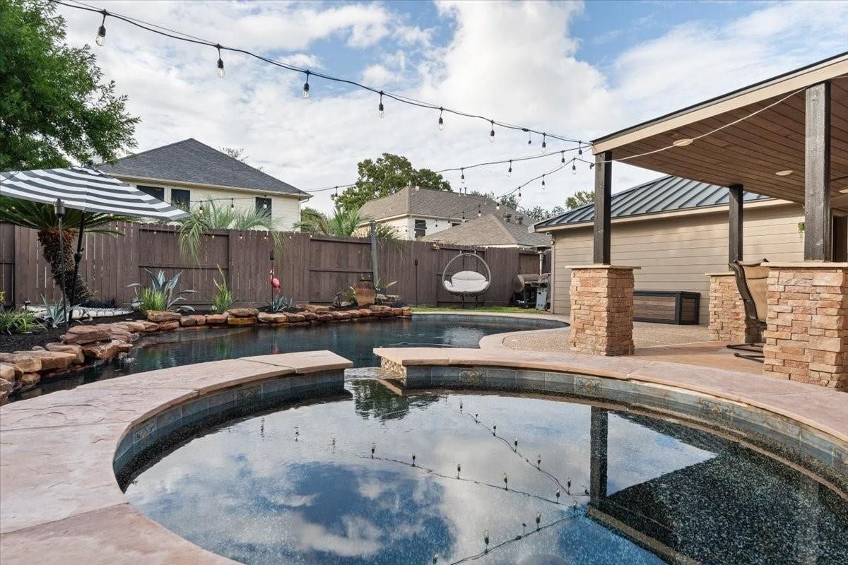 2437 La Rochelle Court, Seabrook, TX 77586 Inviting pool and raised spa framed by stone coping, landscaping, and a covered outdoor living area.