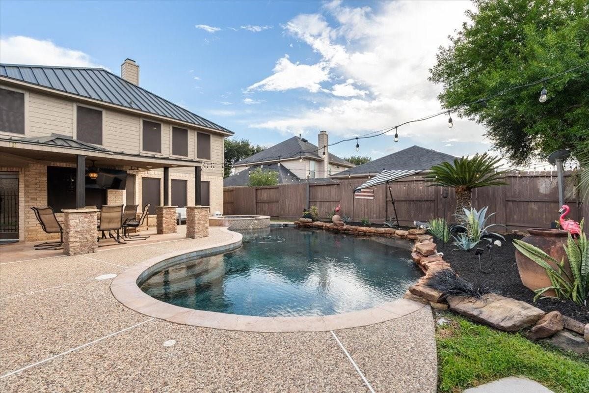 2437 La Rochelle Court, Seabrook, TX 77586 A sweeping backyard view showcases the swimming pool, covered entertaining patio, and landscaped surroundings.