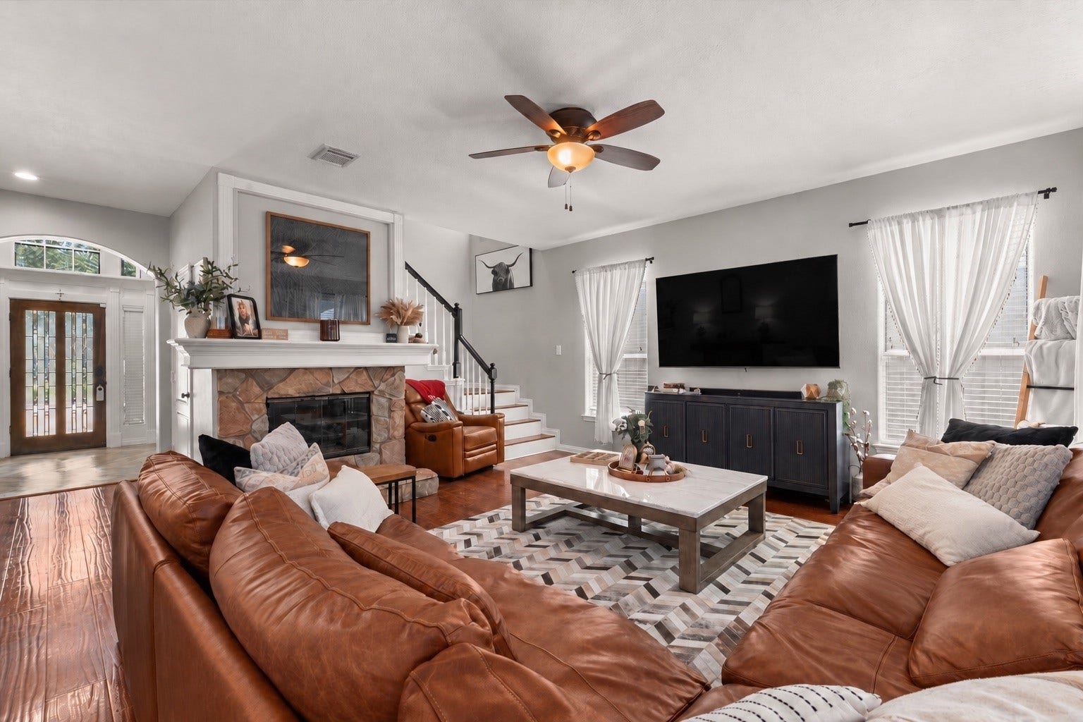 2437 La Rochelle Court, Seabrook, TX 77586 Spacious family room features a stone fireplace, wood flooring, abundant windows, and comfortable seating areas.