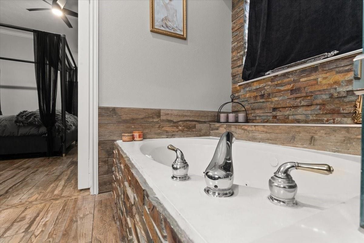 2437 La Rochelle Court, Seabrook, TX 77586 Soaking tub is surrounded by textured stone finishes, creating a distinctive primary bath retreat.