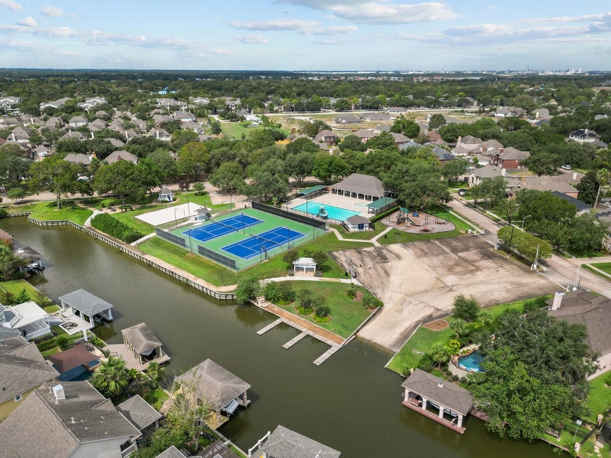 2437 La Rochelle Court, Seabrook, TX 77586 Aerial view shows neighborhood recreation facilities including a pool, sports courts, neighborhood boat ramp and playground near the water.