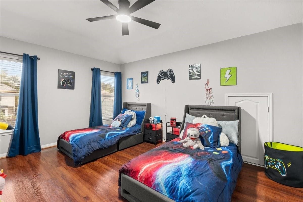 2437 La Rochelle Court, Seabrook, TX 77586 Light-filled secondary bedroom offers wood flooring, a ceiling fan, and room for two beds.