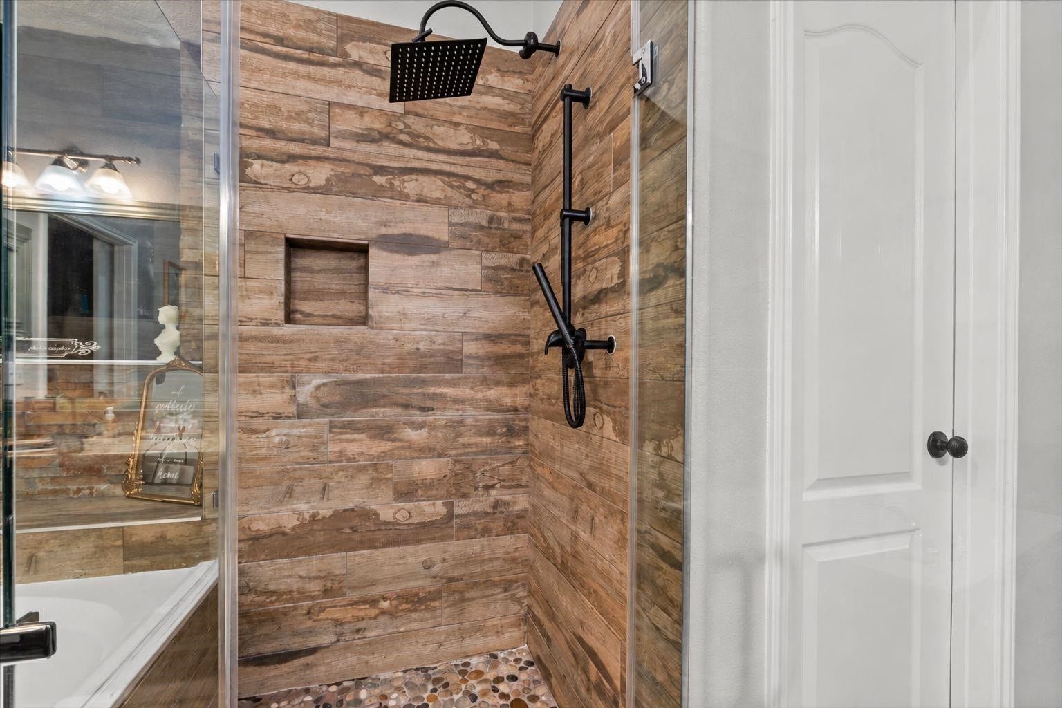 2437 La Rochelle Court, Seabrook, TX 77586 Glass-enclosed shower features wood-look tile, a pebble-style floor, and rainfall showerhead.
