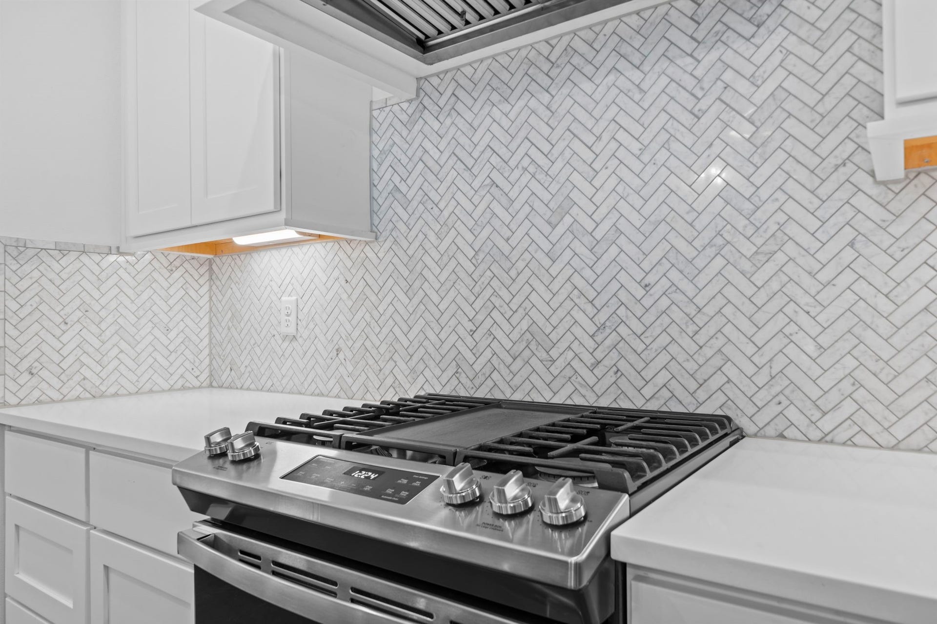 1128 Malone Street, Houston, TX 77007 The gas cooktop, custom vent hood, and herringbone-style backsplash create a strong kitchen detail.
