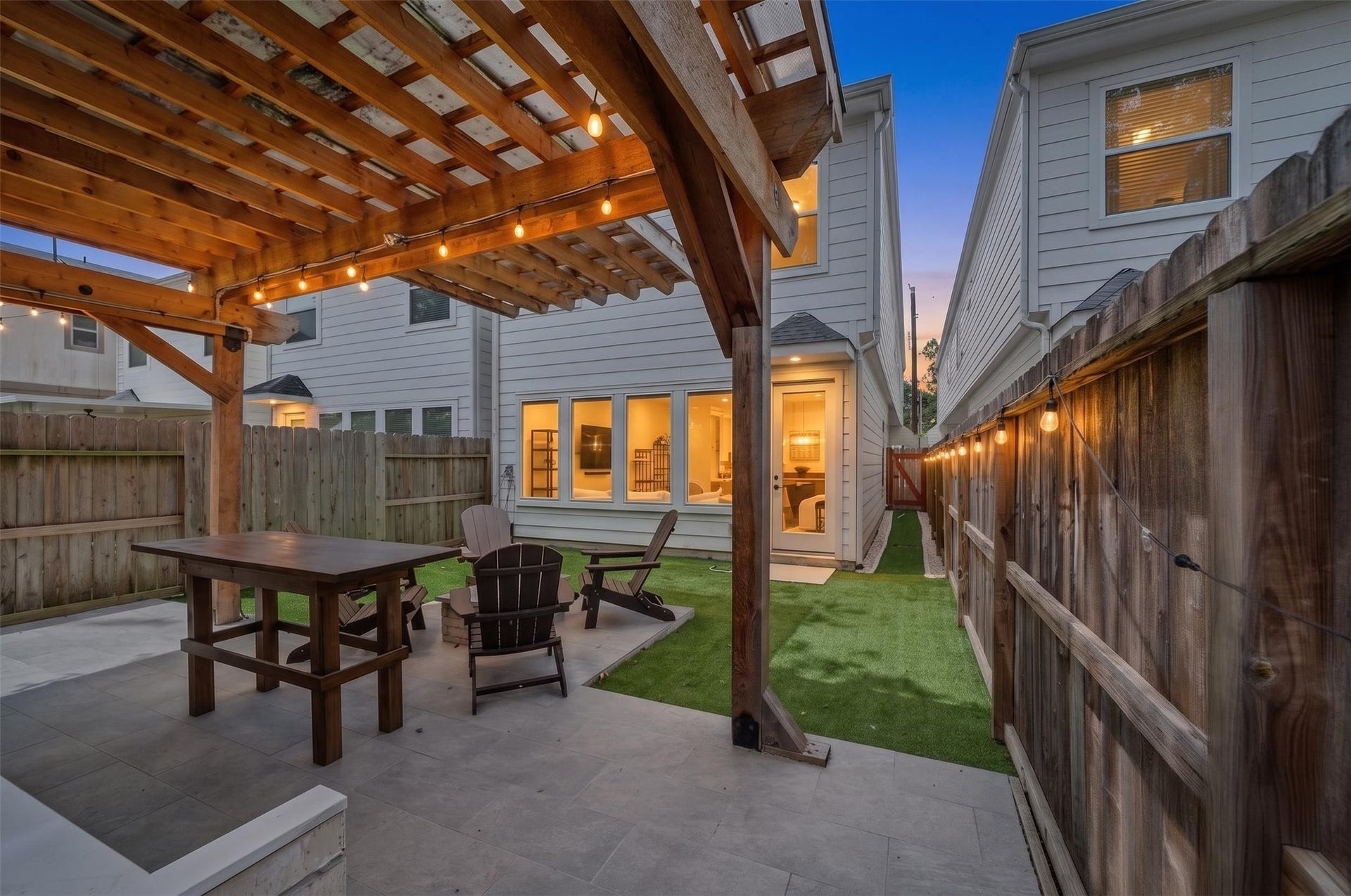 1128 Malone Street, Houston, TX 77007 The covered patio and pergola create a finished outdoor living area just beyond the main level. Artificial turf and the outdoor fireplace make the backyard feel intentionally designed. Virtually altered.