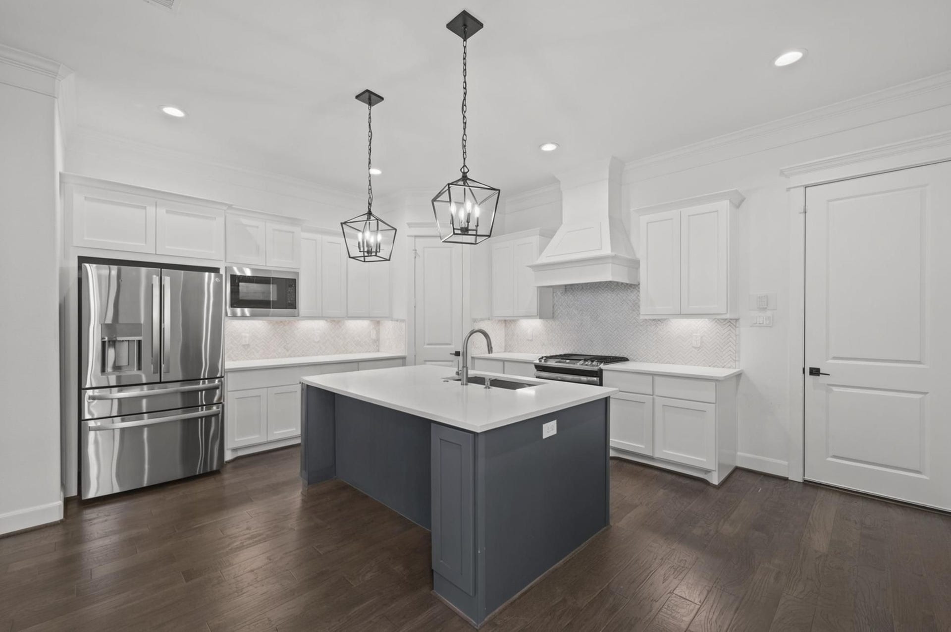 1128 Malone Street, Houston, TX 77007 The kitchen continues with white cabinetry, stainless steel appliances, and a large island that anchors the room. The design feels bright, functional, and current.