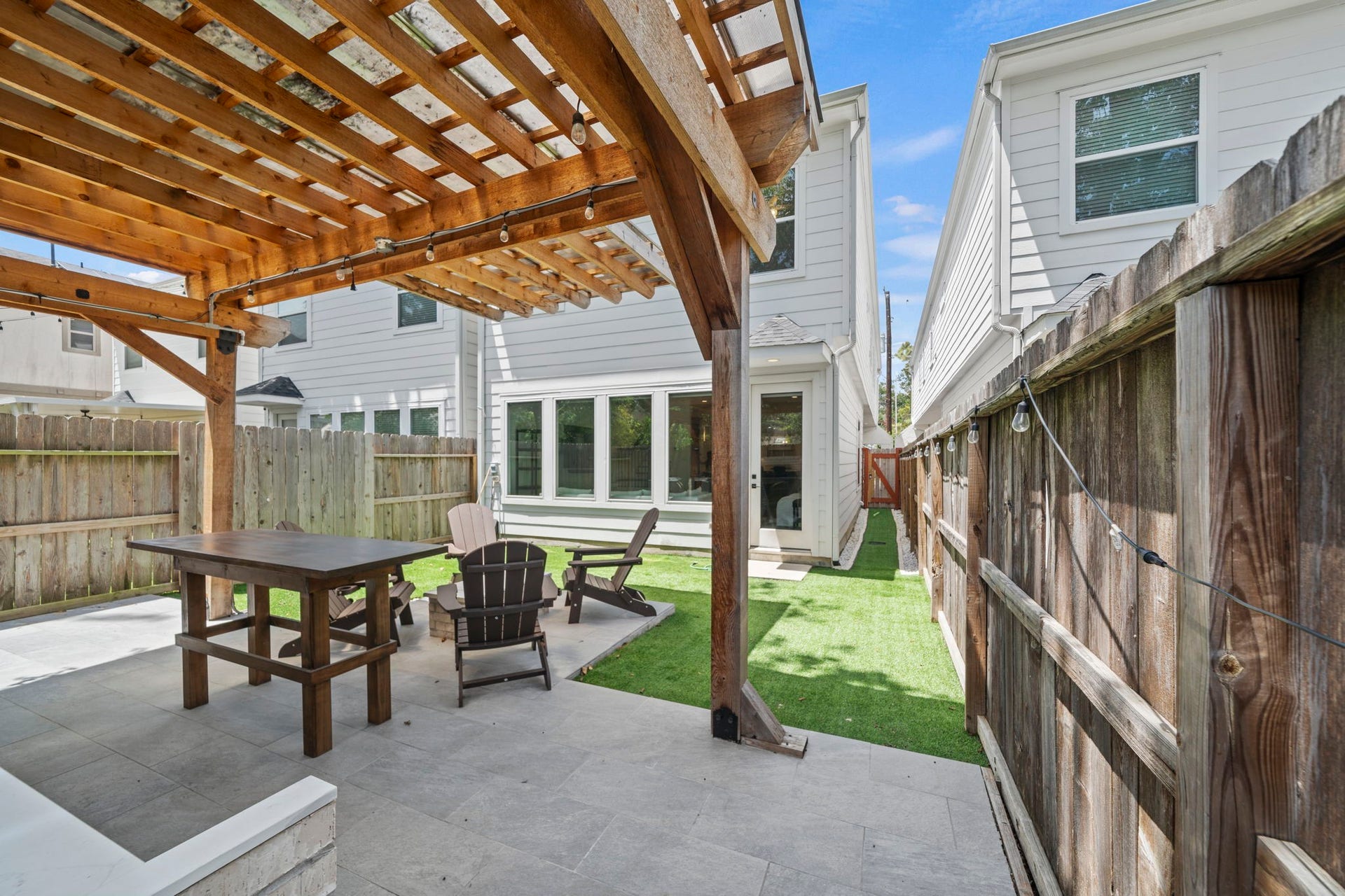 1128 Malone Street, Houston, TX 77007 The covered patio offers another look at the outdoor setup, showing how the pergola, turf, and side access all connect. It creates a practical flow from the home to the backyard.