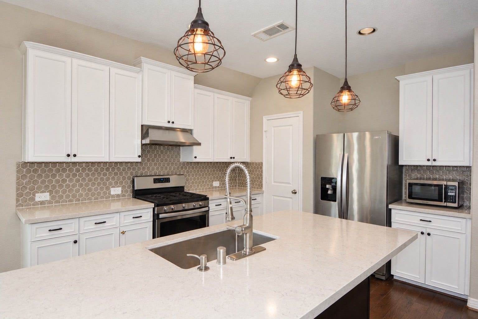 26322 Stonedale View Drive, Richmond, TX 77406 Alternate view of the kitchen showcasing stainless steel appliances, a large island, a modern sink, and modern lighting fixtures