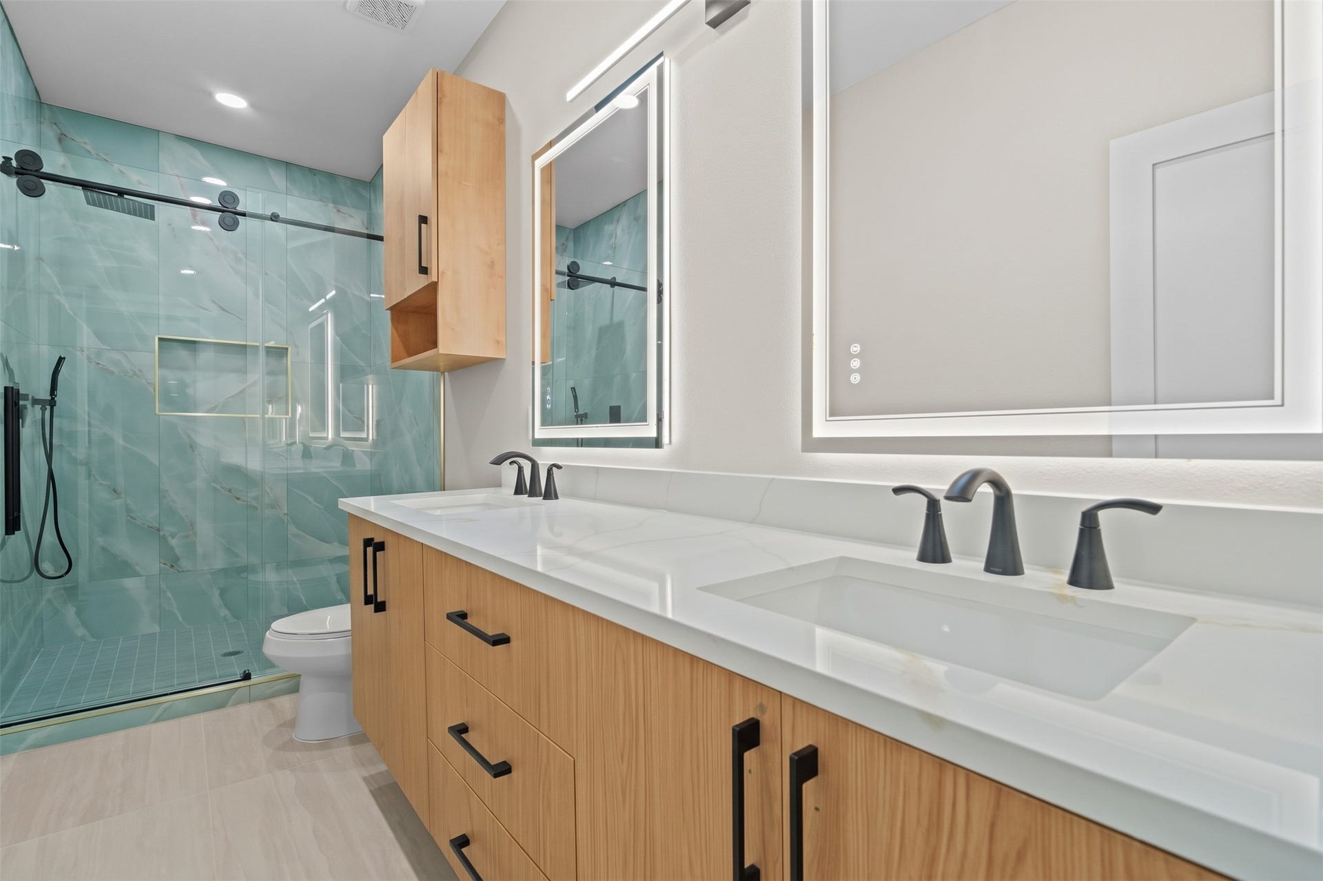 Modern functionality meets elevated design in this primary bath suite. Features include an elongated vanity layout with integrated lighting, dual sinks, and a walk-in glass shower.