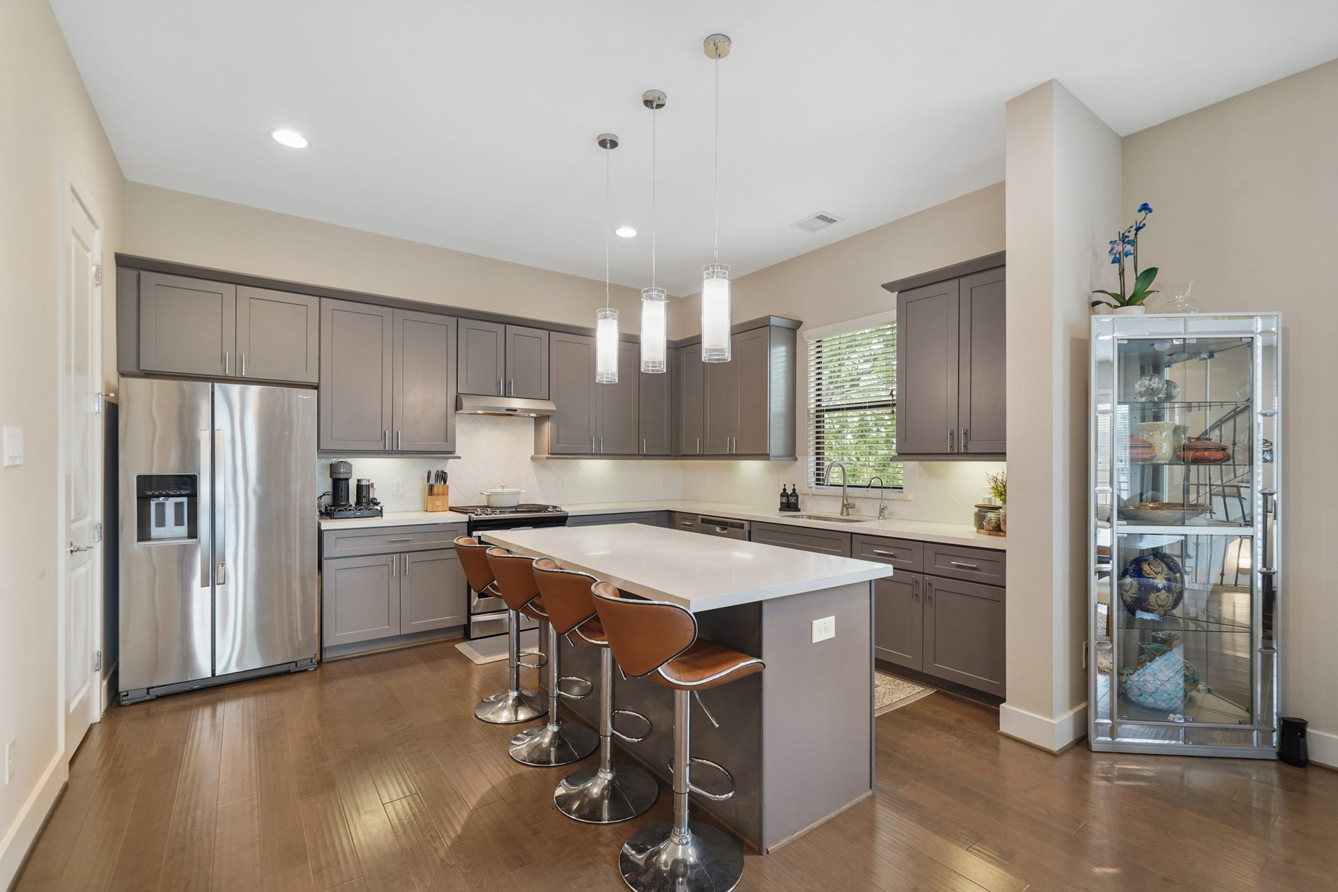 1824 Bonner Street, Houston, TX 77007 The kitchen sits on the back of the home with a high ceiling, 42" painted Shaker-style cabinets capped with crown moulding, quartz counter tops highlighted by a herringbone patterned and subway tiled back splash with under cabinet lighting & hardwood floors.