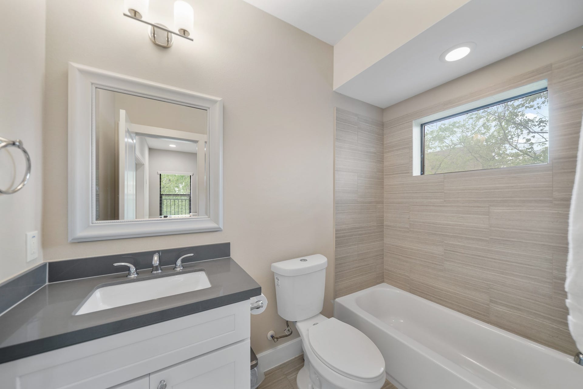 1824 Bonner Street, Houston, TX 77007 Serving as the home's third full bath, this bath includes a painted Shaker-style cabinet supporting a quartz counter with integrated back splash, framed mirror with lighting above, a ceramic tile surrounded combination tub/shower with window above & tile flooring.