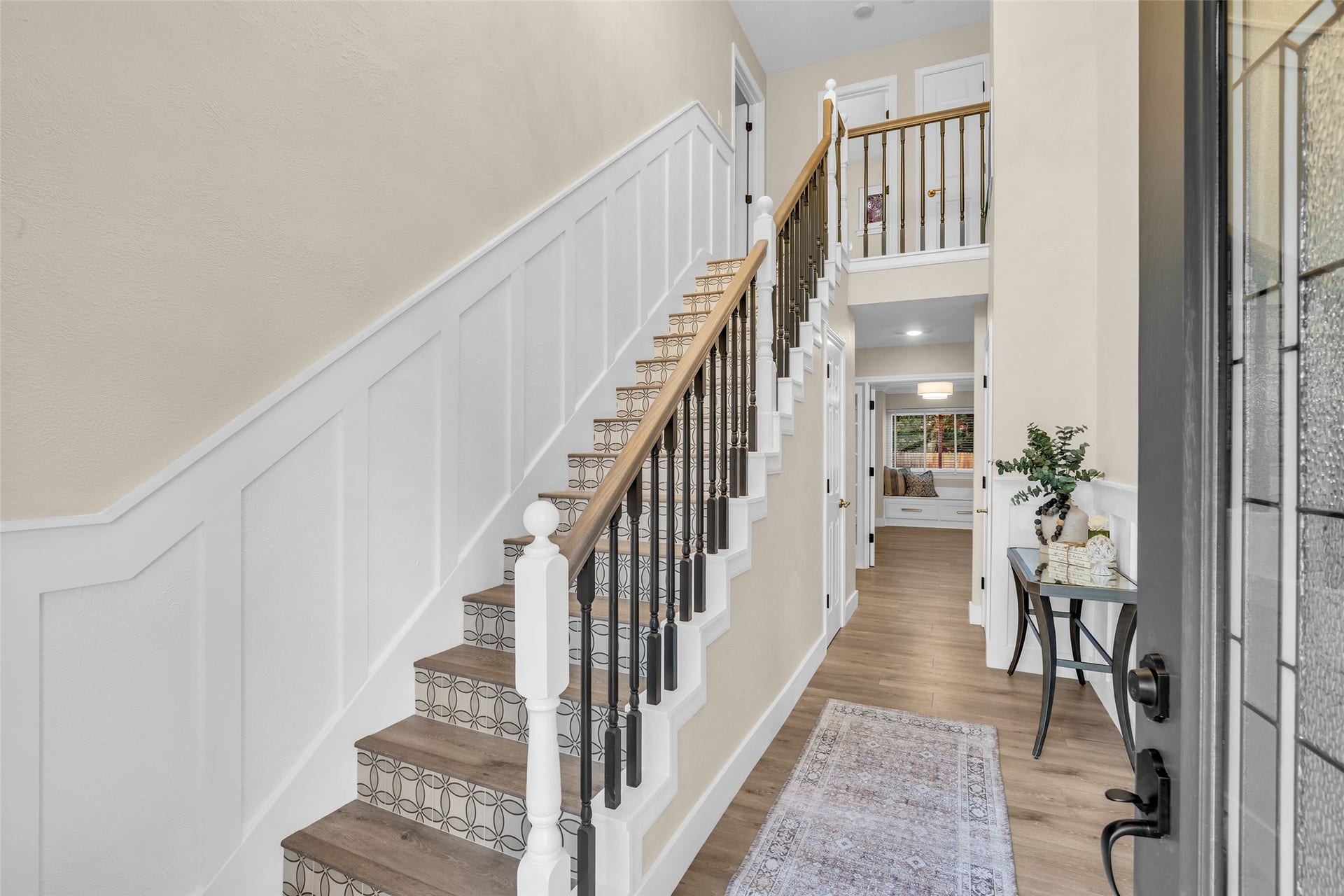Statement entryway with wainscotting, tiled stair risers and a stunning chandelier. Imagine this decorated for the Holidays!