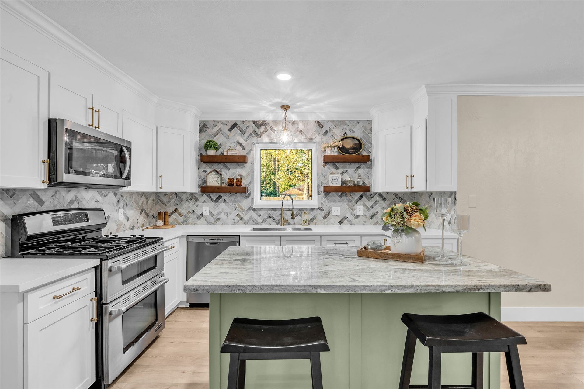 This kitchen makes an absolute statement, custom cabinetry and floating shelves framing in the window overlooking the spacious back yard and deck.