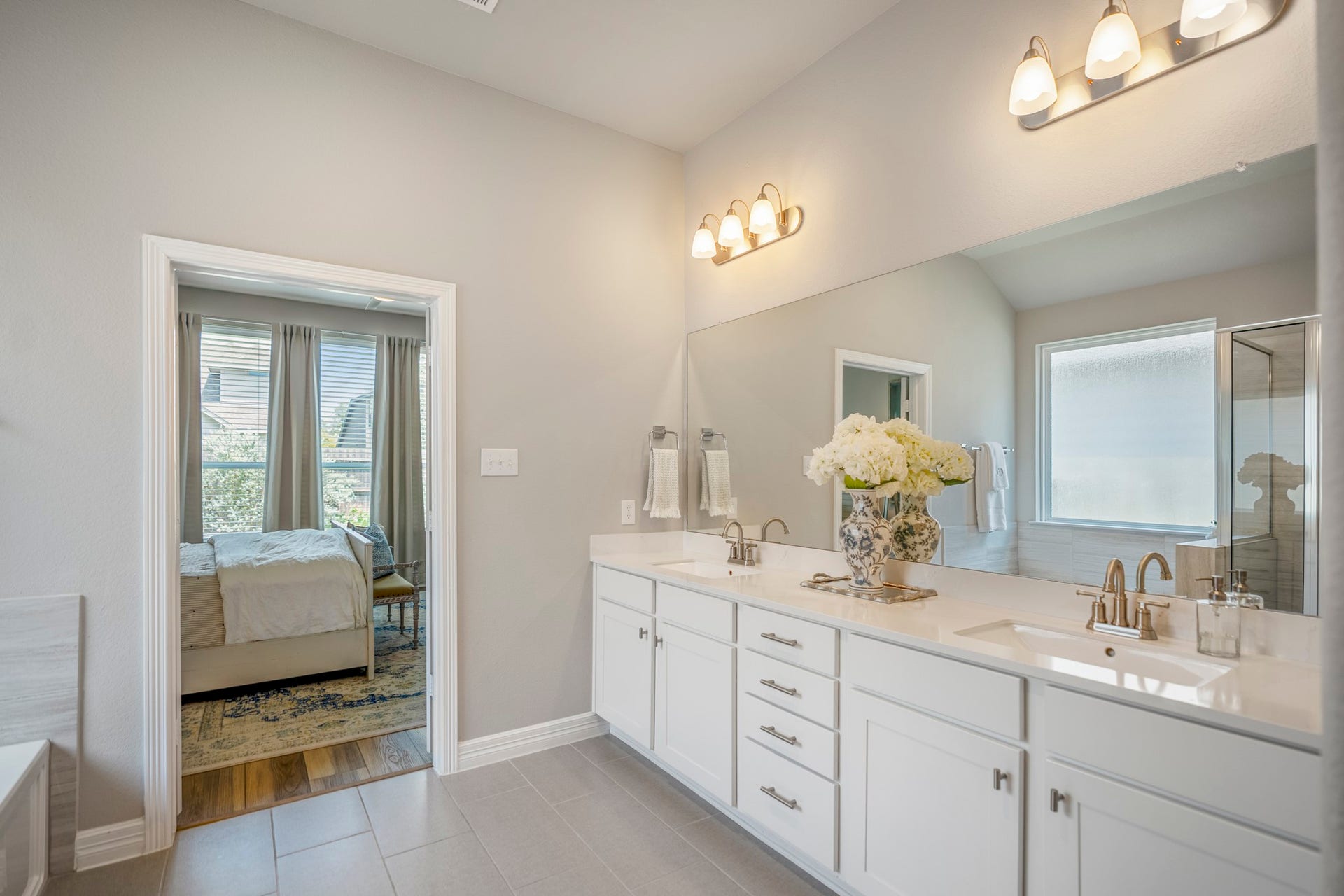 Primary Bathroom with double sinks, extended vanity and tile flooring.