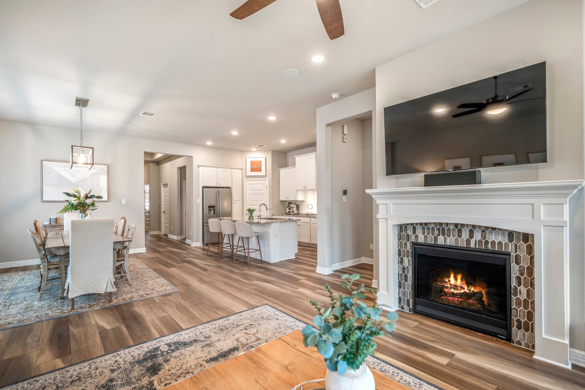 Spacious living room with luxury vinyl plank flooring throughout and a cozy gas fireplace featuring the most beautiful tile surround.