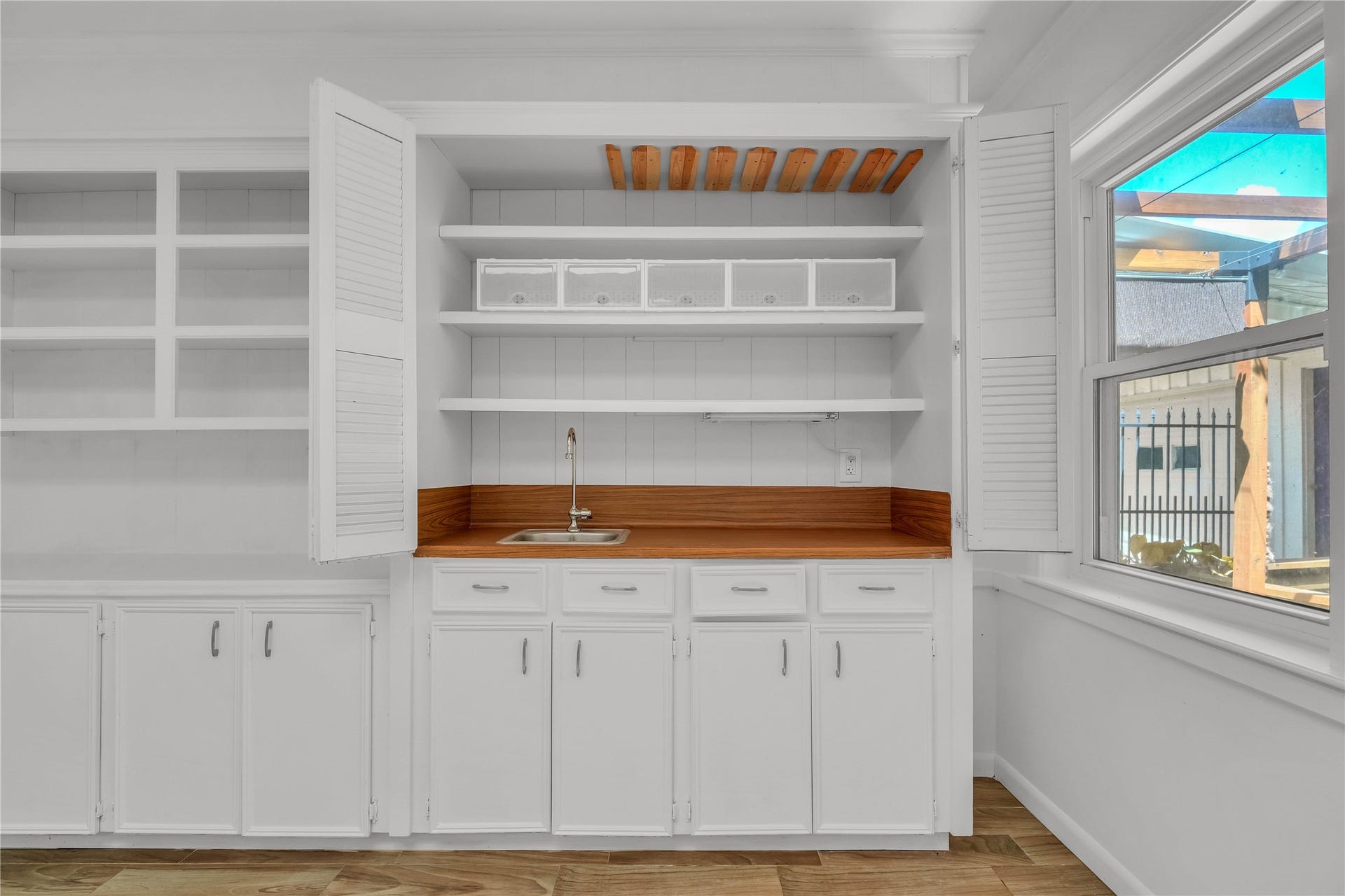 10818 Elmdale Drive, Houston, TX 77070 Built-in cabinetry and shelving offer ample storage and display space, complemented by a convenient sink area within the sunroom.