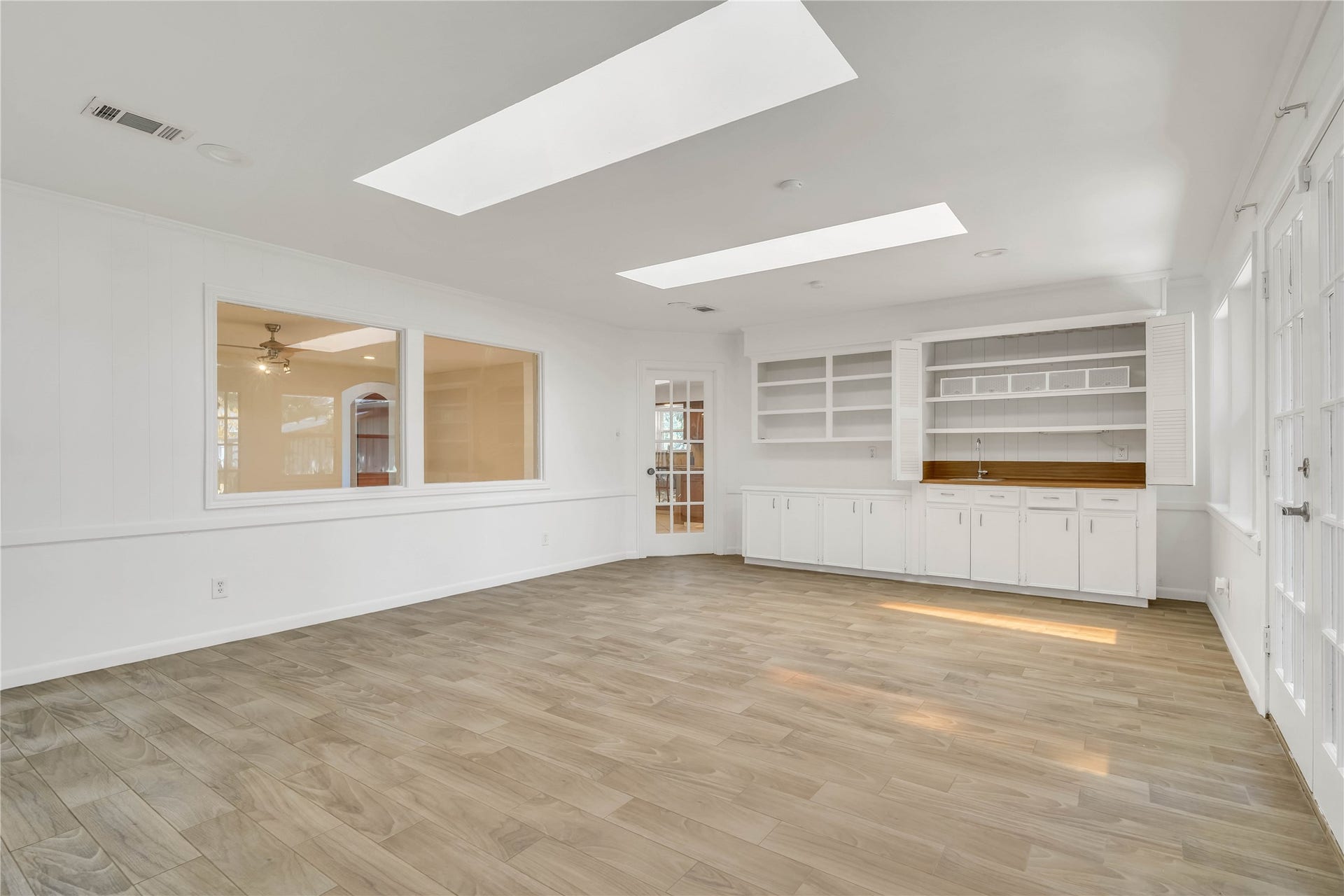 10818 Elmdale Drive, Houston, TX 77070 This perspective highlights the sunrooms generous size, abundant natural light from multiple windows and skylights, built-in storage, and flexible layout, ideal for a game room, playroom, hobby space, or additional entertaining area.