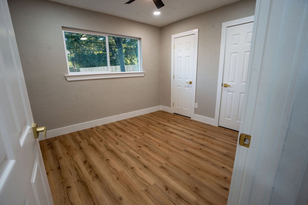 9856 Oriole, Conroe, TX 77385 Bright and cozy room featuring elegant vinyl flooring, ample natural light from a large window, and convenient double-door closets.