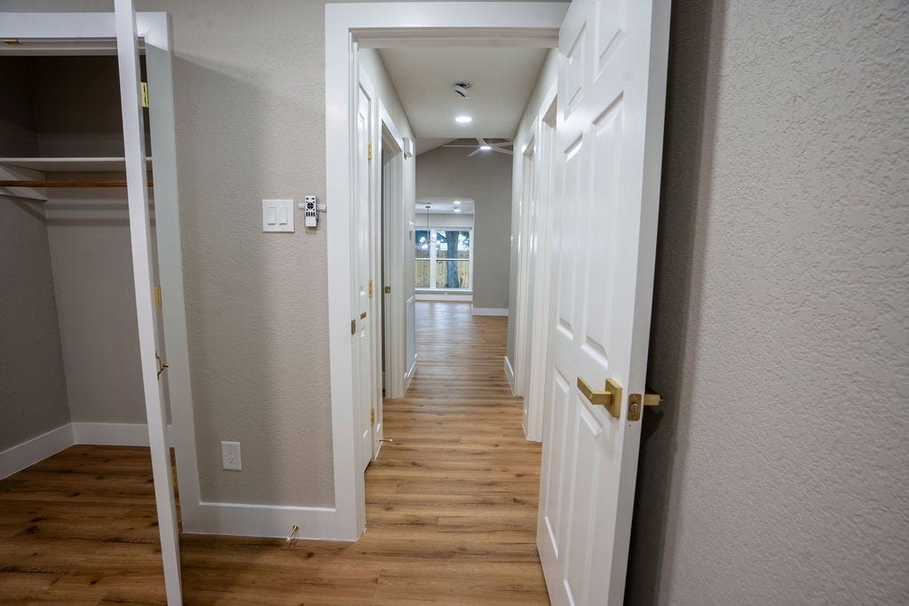 9856 Oriole, Conroe, TX 77385 Bright hallway with elegant wood flooring leads to spacious rooms, featuring modern white doors and ample natural light.