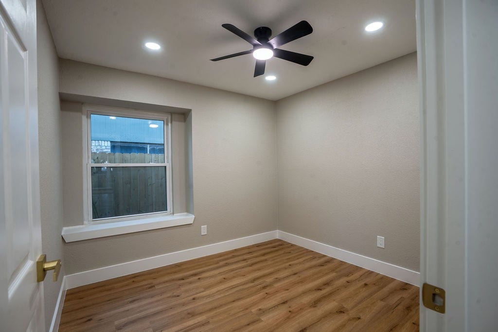9856 Oriole, Conroe, TX 77385 Cozy room with elegant wood style flooring, a large window for natural light, and a modern ceiling fan.