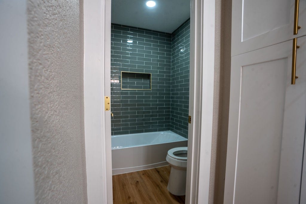 9856 Oriole, Conroe, TX 77385 Stylish bathroom featuring sleek gray subway tiles, a modern bathtub, and elegant wood style flooring, creating a contemporary and inviting space.