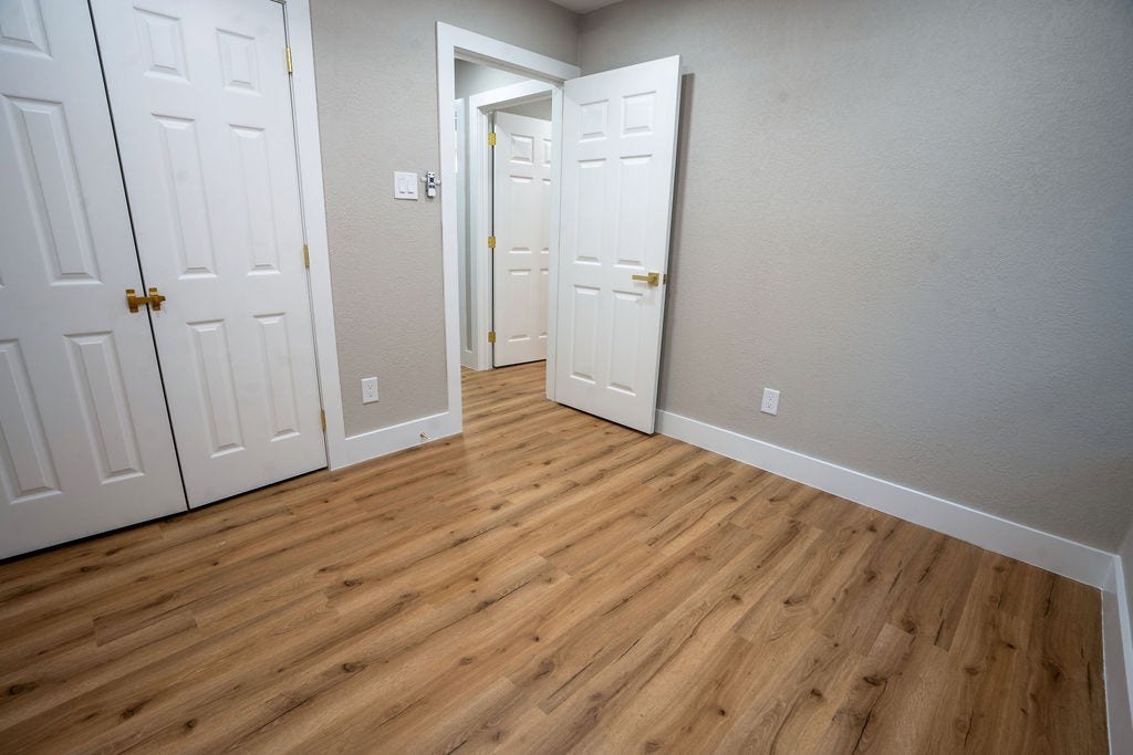 9856 Oriole, Conroe, TX 77385 Bright and cozy room featuring elegant wood style flooring, ample closet space, and fresh neutral walls, perfect for a versatile living or office area.