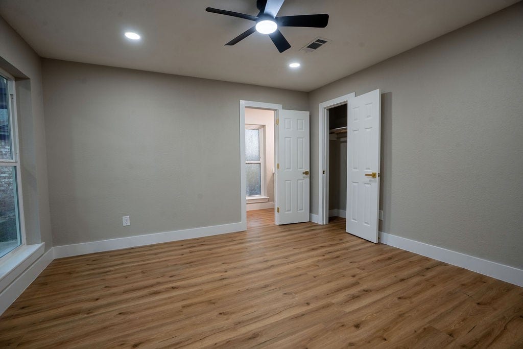 9856 Oriole, Conroe, TX 77385 Spacious bedroom featuring elegant wood style flooring, ample natural light from large windows, and a modern ceiling fan.