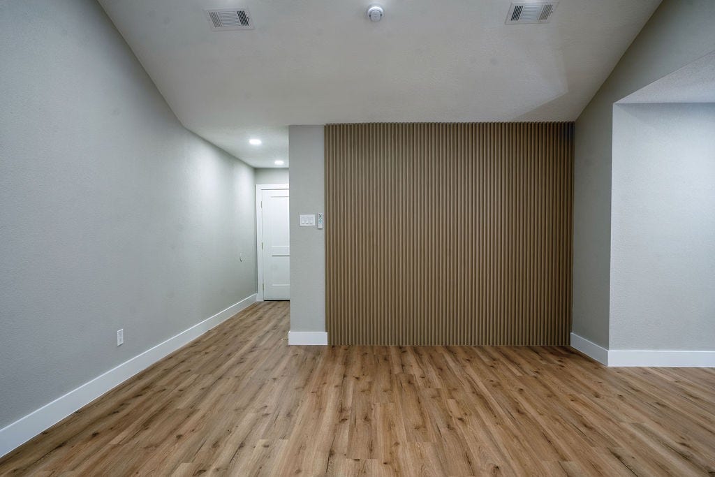9856 Oriole, Conroe, TX 77385 Stylish interior with wood-look flooring and a modern accent wall, creating a cozy yet contemporary atmosphere.