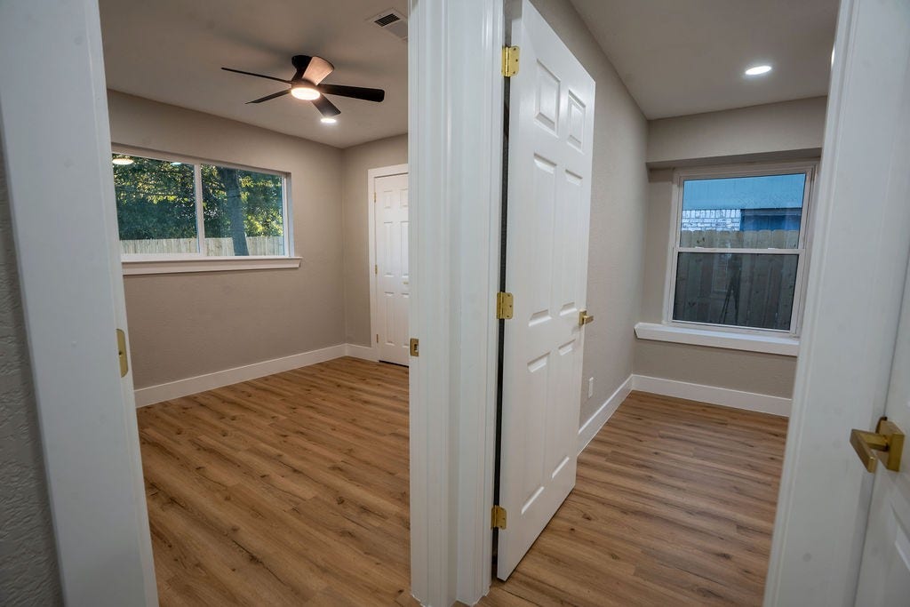 9856 Oriole, Conroe, TX 77385 Bright and inviting room with elegant wood style flooring, large windows for natural light, and a modern ceiling fan.