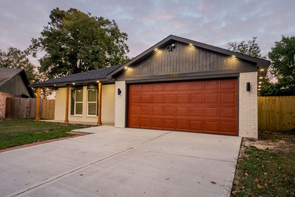 9856 Oriole, Conroe, TX 77385 Charming single-story home with a modern faade featuring a spacious two-car garage, elegant exterior lighting, and a welcoming front porch.