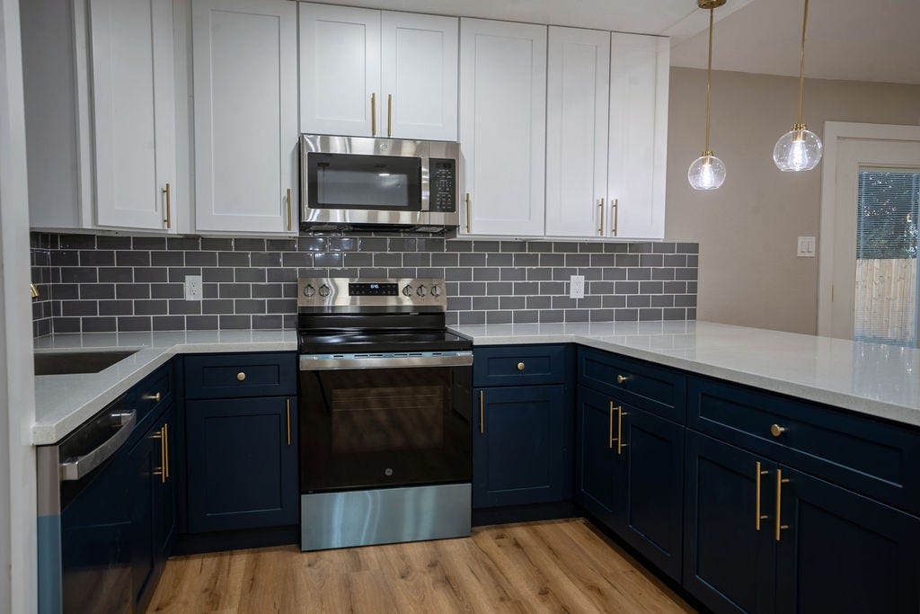 9856 Oriole, Conroe, TX 77385 Chic kitchen with modern stainless steel appliances, elegant two-tone cabinetry, and stylish pendant lighting.